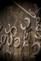 Multiple horseshoes and chains nailed on an old wooden door photo