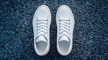 Fresh white sneakers positioned on textured dark surface during daylight photo