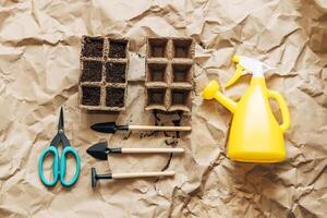 Kraft paper background, fertile soil and garden tools on top, top view. Planting seedlings in spring photo