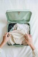 A person is opening an open suitcase with clothes inside photo