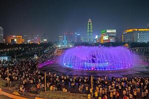 Illuminated fountain show at Quancheng Square in Jinan China with crowds at night a photo