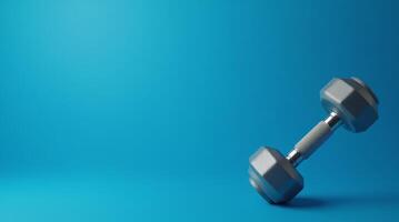Gray dumbbell with textured metal handle placed on blue background, fitness concept for gym, strength training, and healthy lifestyle design with copy space photo