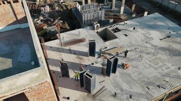 Workers at construction site preparing reinforced concrete foundation, surrounded by building materials and structures. video