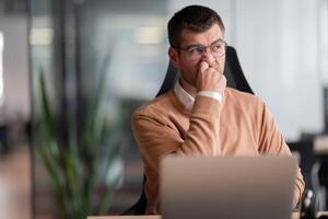 Funny scene of a businessman putting a finger in his nose. Employee in the office, thinking and brainstorming ideas for a startup. Man at workplace working on laptop, copywriting and innovation in a photo