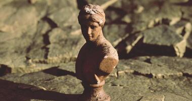 Bust sculpture displayed on textured stone surface in warm light video