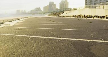 Empty beachside parking area with buildings in the background during sunset video