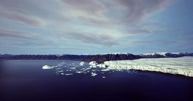 Glacial landscape with floating icebergs in calm waters during daytime video