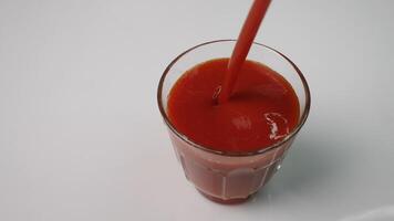 A vivid image shows fresh tomato juice being poured into a glass, highlighting its rich, alluring color photo