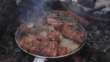 Delicious pieces of meat are sizzling in a pan over a captivating open fire, creating a rich smoky atmosphere photo