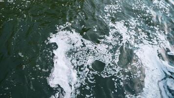 A captivating and mesmerizing view of a shimmering water surface showcasing swirling currents and frothy foam photo