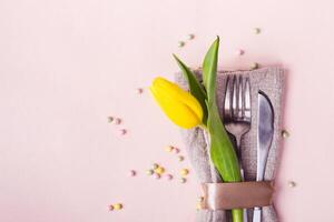 Spring Easter table setting. Cutlery is decorated with beautiful yellow tulip close-up photo