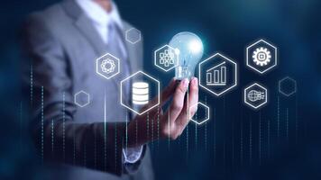 Businessman holding light bulb with digital transformation innovation and technology icons, data analysis, automation, and business strategy photo