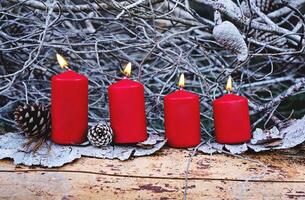 Four red burning advent candles as Catholic symbol of Christmas. Christmas decoration with burning candles for Advent time. greeting card concept photo