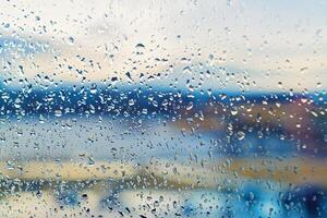 Abstract blurred background street outdoor behind wet window with rain drops, blurred street bokeh. Concept of autumn weather and rainy season, copy space photo