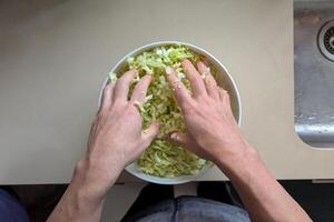 Hands vigorously tossing shredded cabbage in large bowl, salad becoming bright symbol of fresh nutrition, salad capturing crisp texture, salad perfect for quick healthy lunches photo