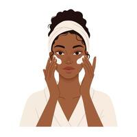 Beautiful african american woman with white towel on her head, using a facial cleansing pad vector