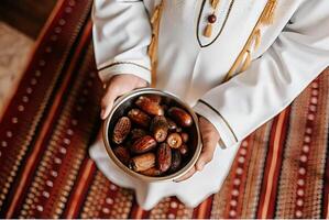 A person in a white robe holding a bowl of dates photo