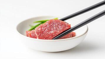 A bowl of beef with chopsticks on top photo