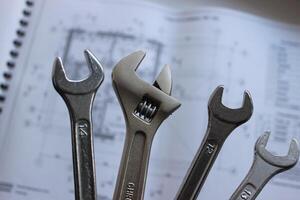Hex spanners and adjustable wrench over defocused paper drawing of a house rooms and premises photo