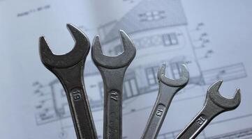 Set of variety size mechanical spanners on background of private house exterior blueprint with the dimensions and construction materials photo