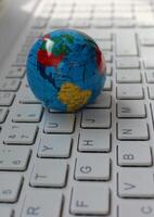 Closeup photo of globe with mapped North and South America continents lying on computer keys angle view