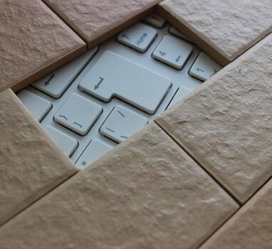 The enter key is visible through a hole in a solid brick wall. Information Security Concept Stock Photo