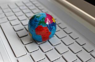 Closeup View Of Globe Model Lying On A Clean Empty Keys Of Computer Keyboard. Global Solutions Concept Stock Image photo