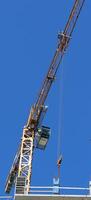 Operator Cabin And Long Boom Of High Rise Construction Crane On Blue Sky Background Vertical Stock Photo