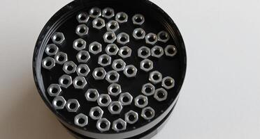 Heap Of Steel Nuts Inside Round Screw Box Closeup Angle View photo