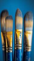 five paint brushes with blue paint on a blue background photo