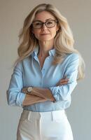 confident senior caucasian woman arms crossed looking at camera on solid neutral background photo