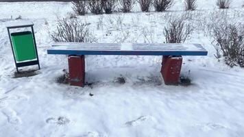 Street bench and trash can covered with snow in winter video