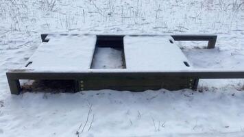 A closed children's sandbox is covered with snow in winter, light snow is falling video