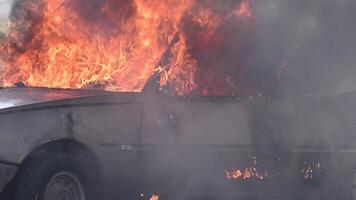 A car is on fire, with flames engulfing the vehicle. Smoke billows from the burning car video
