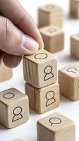 Hand Arranging Wooden Cubes with Person Icons on White Background photo