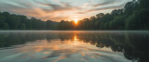 A lake with trees and the sun rising over it photo
