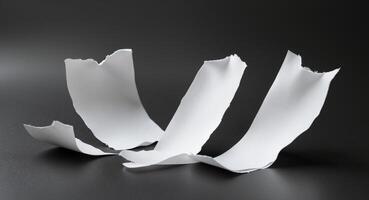 Three torn white paper sheets on black background. photo