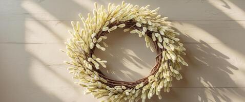 Bright and colorful willow wreath adorned with soft catkins on textured light wooden surface photo