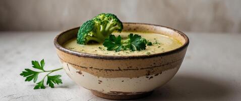 creamy broccoli soup in a rustic bowl garnished with fresh broccoli and parsley. photo