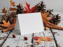 Autumn leaves and acorns on a wooden table with a blank card photo