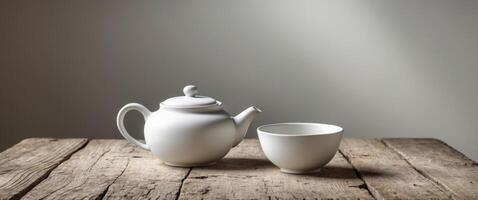 A white teapot and cup on a wooden table photo
