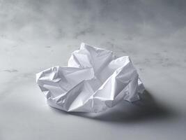 A Single Sheet of Crumpled White Paper on a Smooth Gray Surface A Textured Background Image for Design Projects. photo