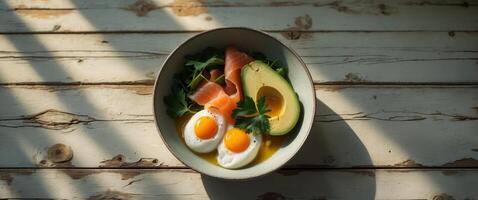 Healthy breakfast bowl with avocado eggs and salmon on a rustic wooden table. photo
