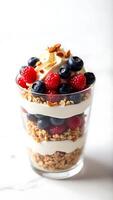 Closeup view of layered yogurt parfait with berries and granola in a clear glass photo