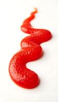 Extreme closeup of a squiggly line of ketchup on a plain surface photo