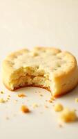 Closeup of a bite taken out of a soft, crumbly baked cookie on a neutral backdrop photo
