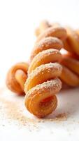 Closeup of a twisted pastry coated with sugar and cinnamon on a plain surface photo