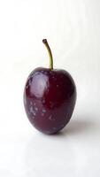 Closeup of a glossy purple fruit with a small stem against a white background photo