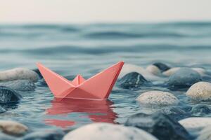 Weakness and damaged concept. A pink paper boat floating on water among smooth stones. photo