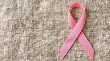 Pink ribbon on textured fabric background symbolizing awareness and support. photo